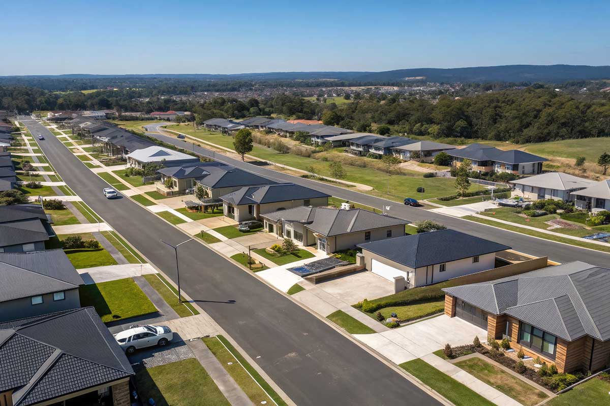 Aerial view of a newly developed residential street with houses, lawns and open green reserve.